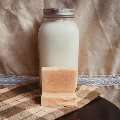 natural colored goat milk soap bars in front of a jar of fresh goat milk.