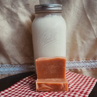 natural color bars of goat milk soap in front of a jar of fresh goat milk.