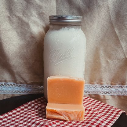 natural colored bars of goat milk soap in front of a jar of fresh goat milk.