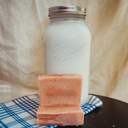 natural colored bar of goat milk soap in front of a jar of fresh goat milk.